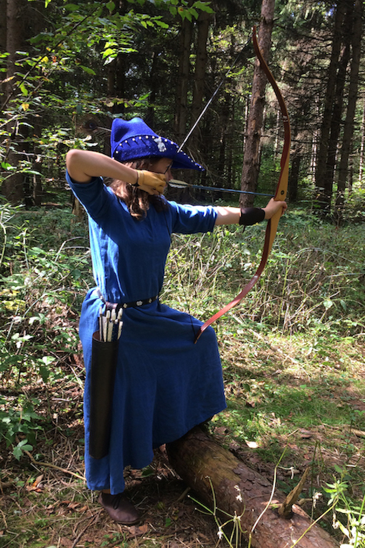 Kelley in medieval dress shooting her bow